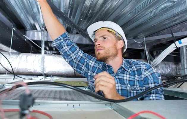 Electrician inspecting area above ceiling