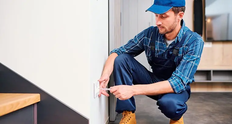 Electrician screwing an electrical outlet plate to a wall